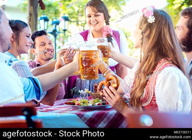 Cheerful group of friends toasting in Bavarian beer garden