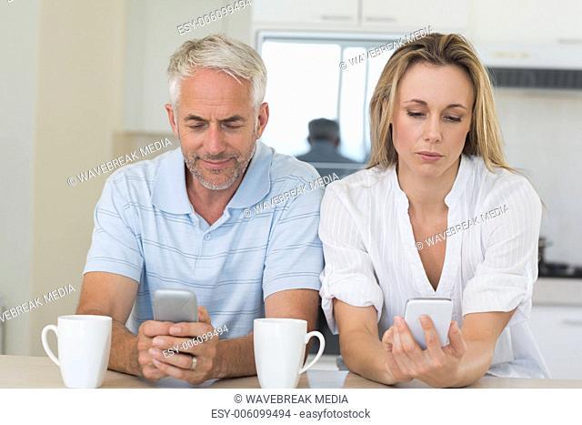 Distant couple sitting at the counter texting and not talking