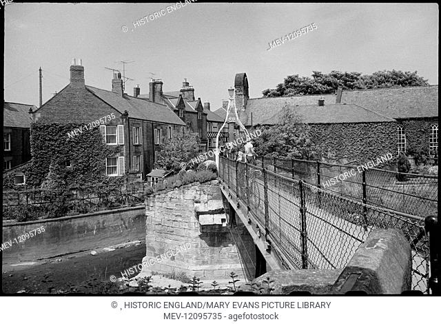 The Old Bridge and Footbridge, spanning the River Wansbeck, with the Chantry in the background, seen from the south. Part of the footbridge were first built in...