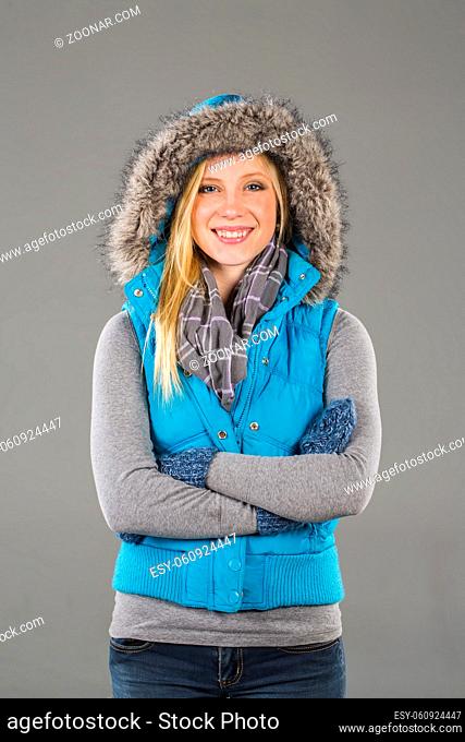 A blonde model poses in a studio environment wearing winter clothing
