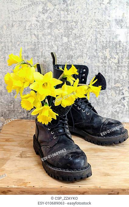 Black military muddy shoes with yellow narcissus