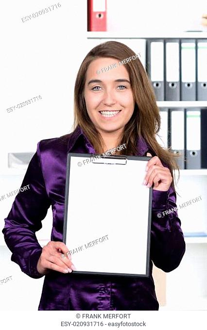 Junge Frau zeigt ein Klemmbrett mit Blatt Papier