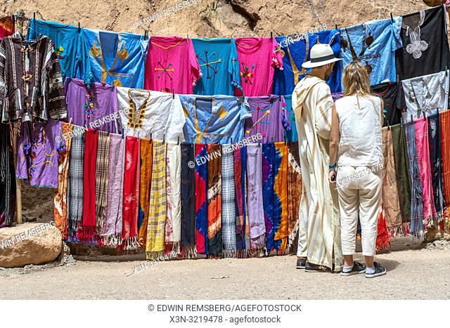 A pair of tourists stop to look at colorful traditional clothing for sale at Todra Gorge, Tinghir, Morocco