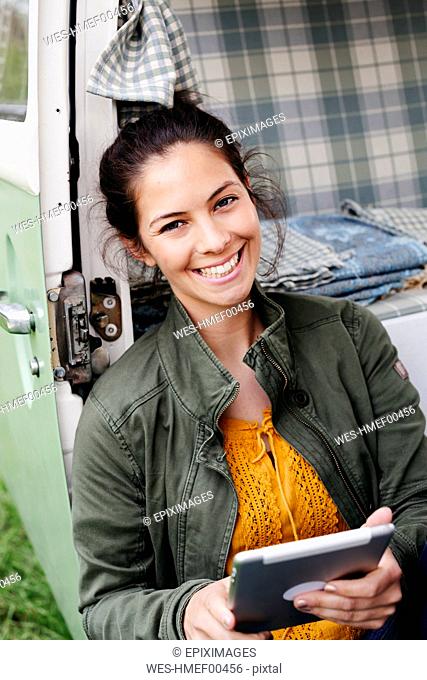 Young woman using digital tablet, sitting in her camper