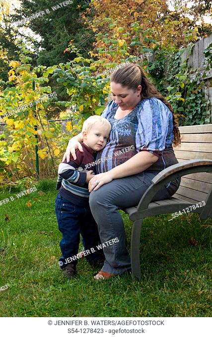 An expectant mother and her two-year-old son outdoors