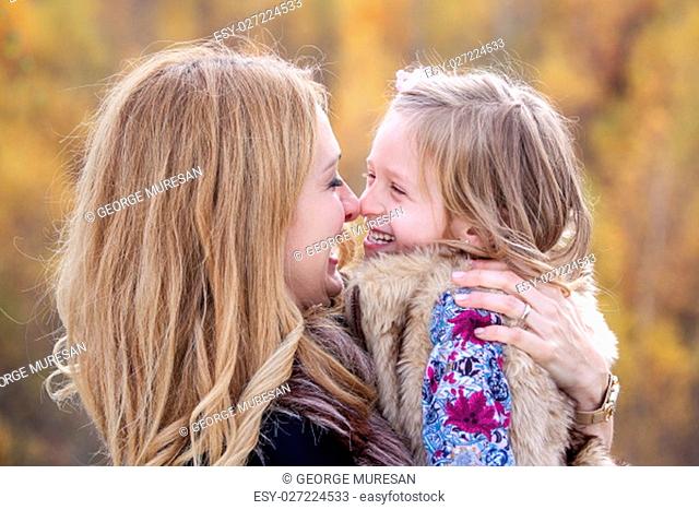 Mother and daughter playing nose to nose in autumn nature