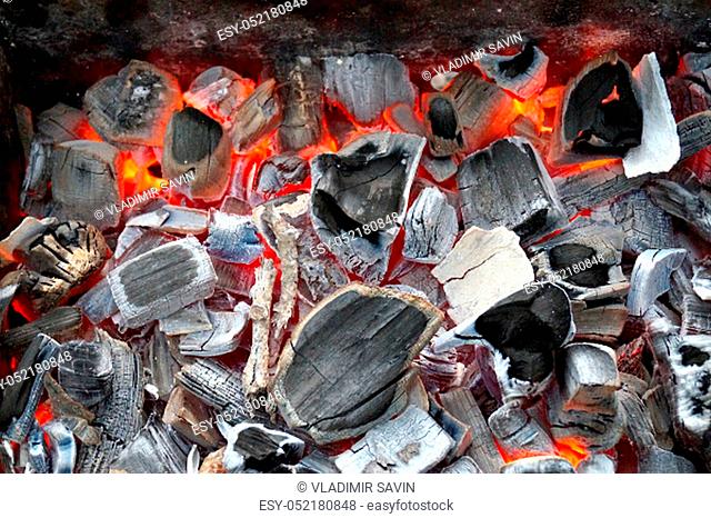 Closeup of black hot coals burning in orange flame. Hot barbeque place