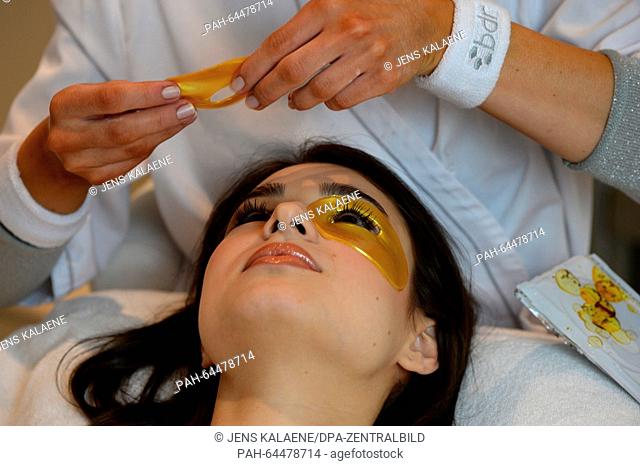 A moisturising eye mask consisting of collagen, hyaluronic acid,  Q10 and vitamins is applied to the face of a young woman as she receives a sun damage repair...