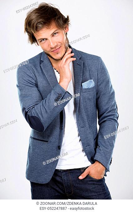 Fashion portrait of a handsome man with trendy hairstyle in a stylish jacket on light background