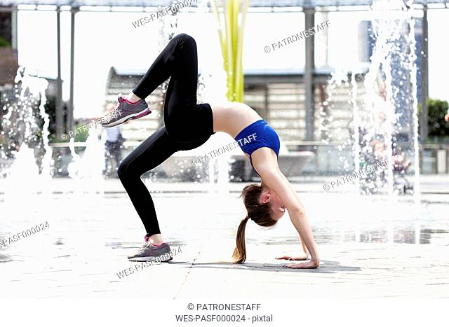 Sportive young woman doing wheel pose in the city