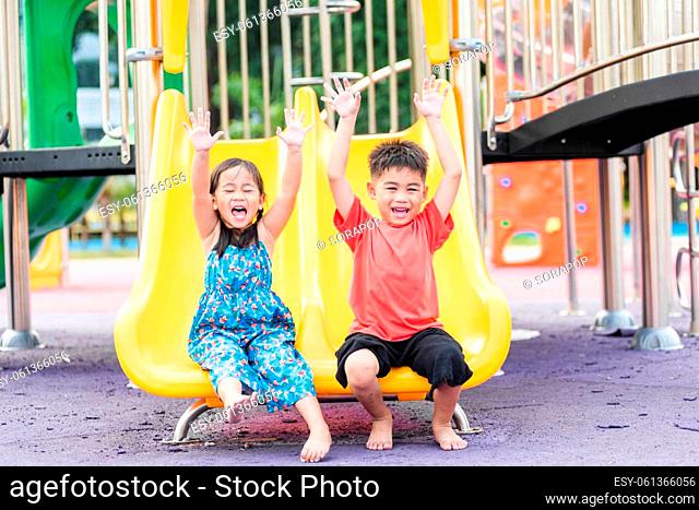 Asian child smiling playing on slider bar toy outdoor playground, happy preschool little kid having funny while playing on the playground equipment in the...