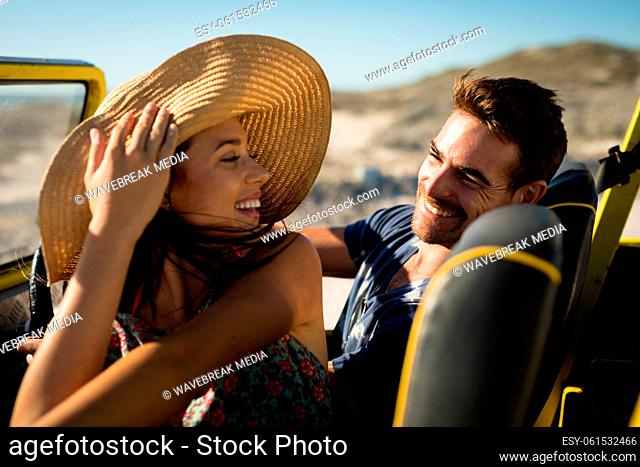 Happy caucasian couple sitting in beach buggy by the sea smiling