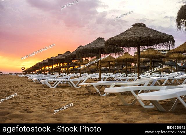 Beautiful colorful sunset over sun beds and umbrellas in Vilamoura, Algarve, Portugal, Europe