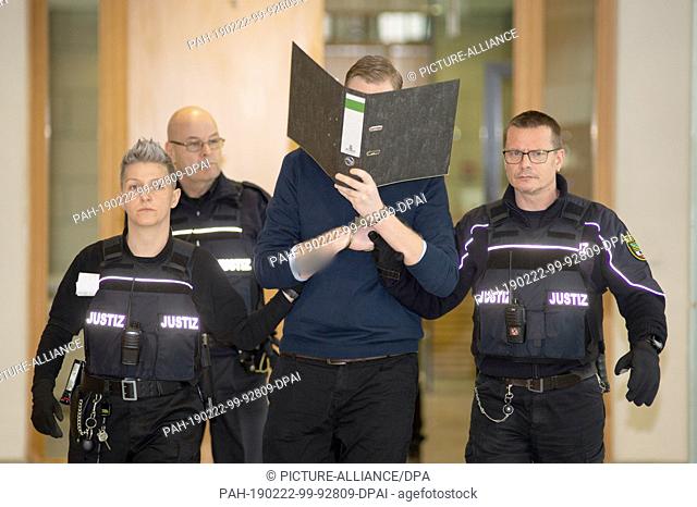 22 February 2019, Saxony-Anhalt, Magdeburg: The defendant (M) is taken to the courtroom in the district court by a number of legal officers