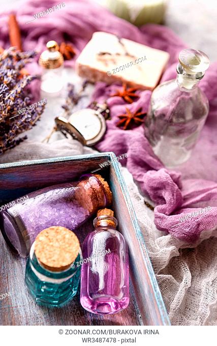 Bottle with aromatic lavender oil and sea salt in a wooden box, a bottle of perfume, a bouquet of lavender, piece of soap and a vintage pocket watch