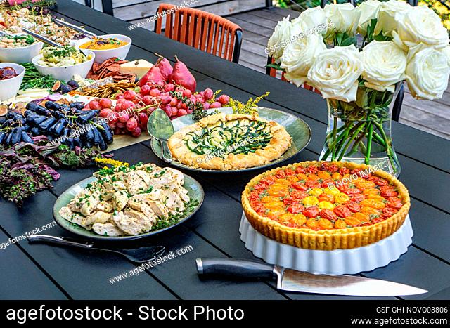Grazing Board with Charcuterie, Tarts, Fruits and Vegetables on Table in Outdoor Setting