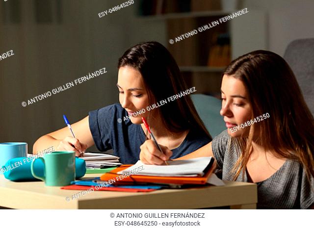 Two students doing homework together in the night at home