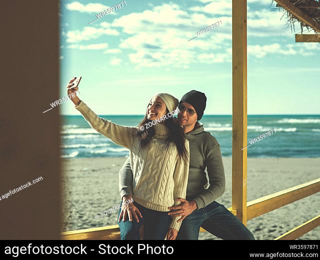 Very Happy Couple In Love Taking Selfie On The Beach in autmun day colored filter