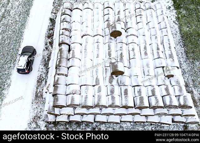 28 November 2023, Brandenburg, Petersdorf: Rolls of straw at the edge of a field are covered with snow (aerial photo taken with a drone)
