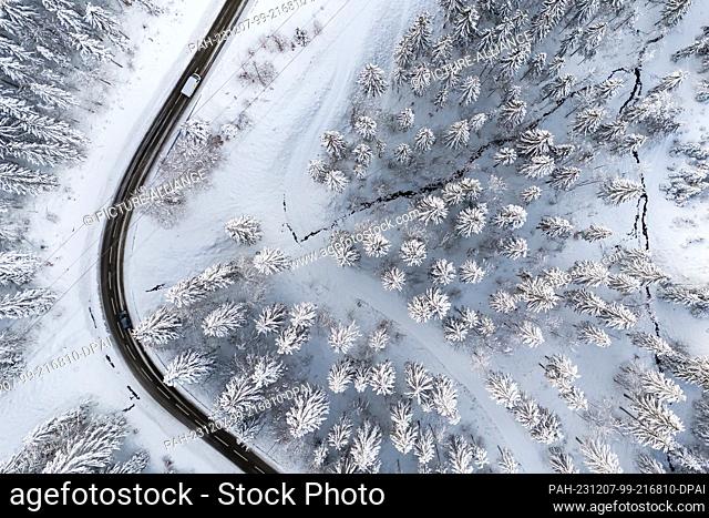 07 December 2023, Baden-Württemberg, Münstertal: Two cars drive along a road through the snow-covered landscape. Due to an inversion