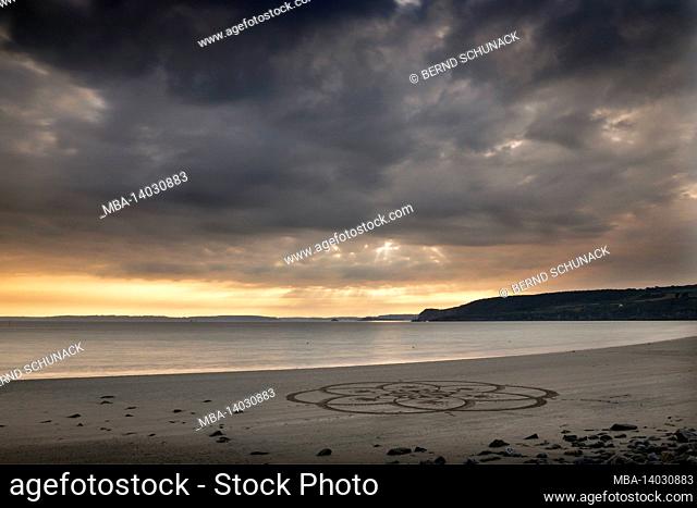 telgruc-sur-mer bay at sunset with a mandala painted on the beach