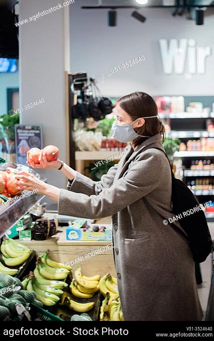 Woman in mask buying fruits at grocery store