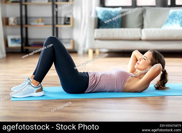 young woman exercising and doing sit-ups at home