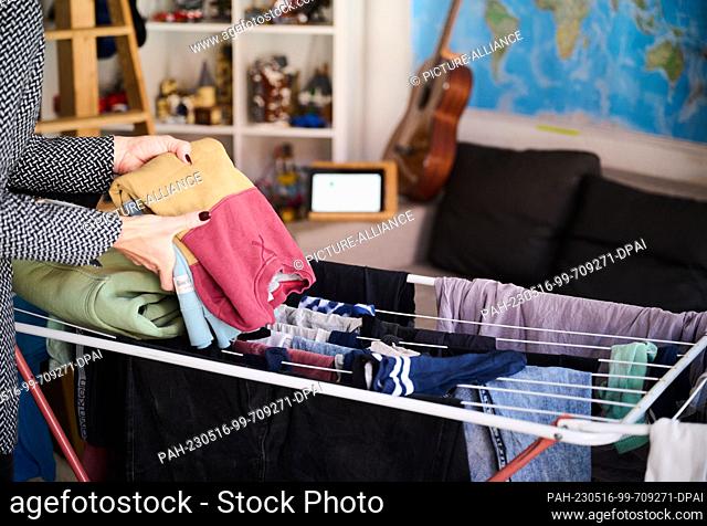 ILLUSTRATION - 05 May 2023, Berlin: A mother participates in a video conference while folding laundry in her child's room. Photo: Annette Riedl/dpa