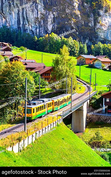 Lauterbrunnen, Switzerland alpine wooden houses in Swiss Alps village in autumn and wengernalpbahn train
