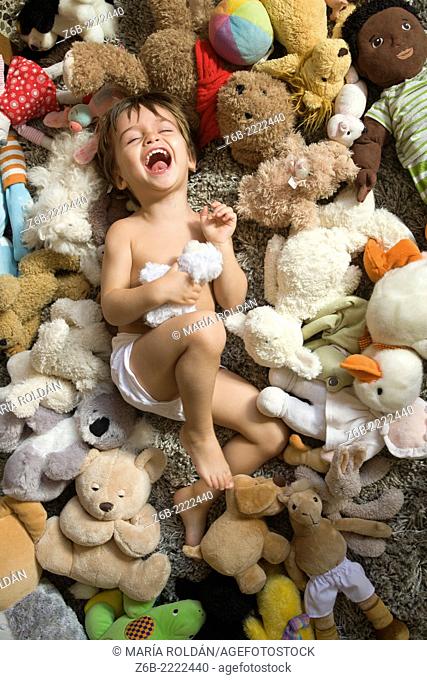 2 years old baby surrounded by stuffed toys