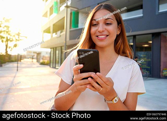 Young attractive woman using smartphone in city at sunset