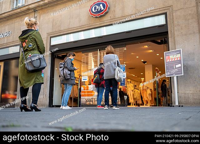 21 April 2021, Saxony, Leipzig: Customers queue outside a fashion store in the centre of Leipzig. The Bundestag votes on Wednesday (21/4) on the federal...