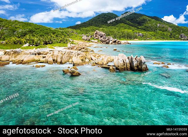 old coral reef in the white sand beach on secluded beach of Grand Anse, La Digue, Seychelles. aerial view