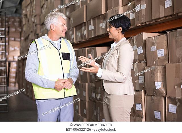 Pretty warehouse manager talking to foreman in a large warehouse
