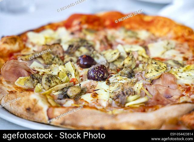 homemade pizza with ham, olives and artichoke