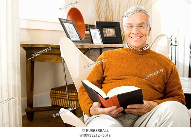 Mature man sitting in chair reading