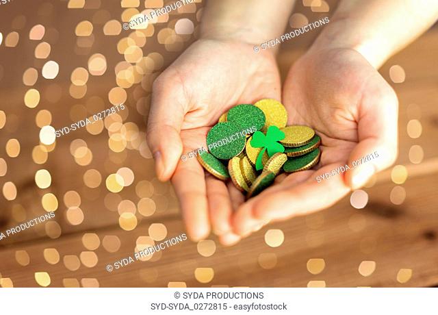 hands with golden coins and shamrock leaf