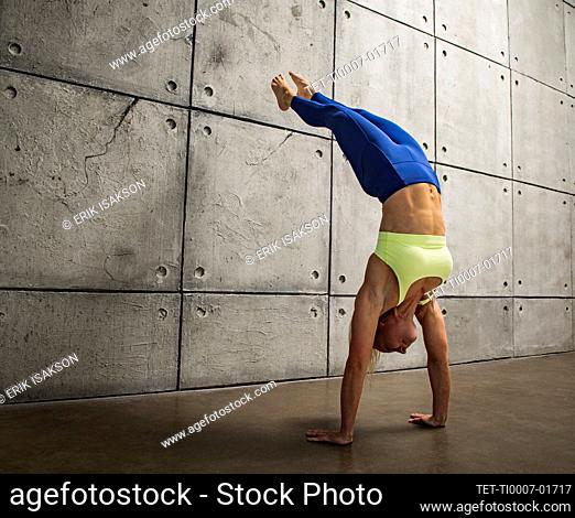 Woman doing handstand against wall