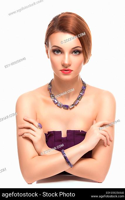 Portrait of beautiful young woman with red hair in natural stones necklace and bracelets. Isolated over white background