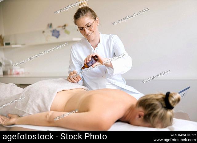 Cupping therapy, female alternative practitioner applying oil for treatment at back