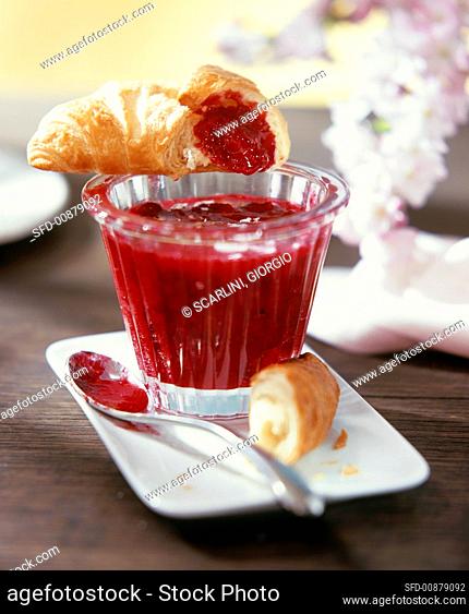 Redcurrant and vanilla jam in a jar with croissant