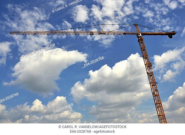 light blue sky with clouds with building crane running horizontally through the image