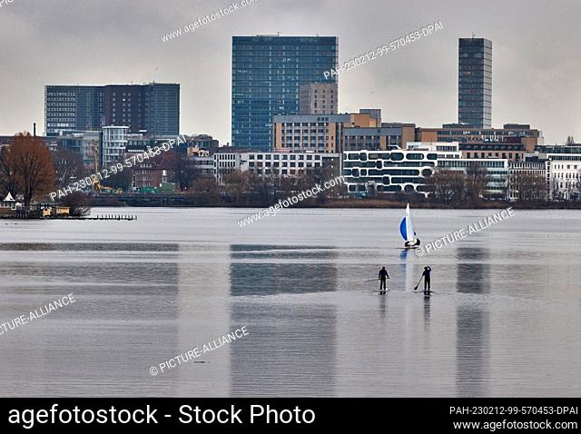 12 February 2023, Hamburg: Two stand-up paddlers are sailing on the Außenalster in a light drizzle. Photo: Georg Wendt/dpa. - Hamburg/Hamburg/Germany