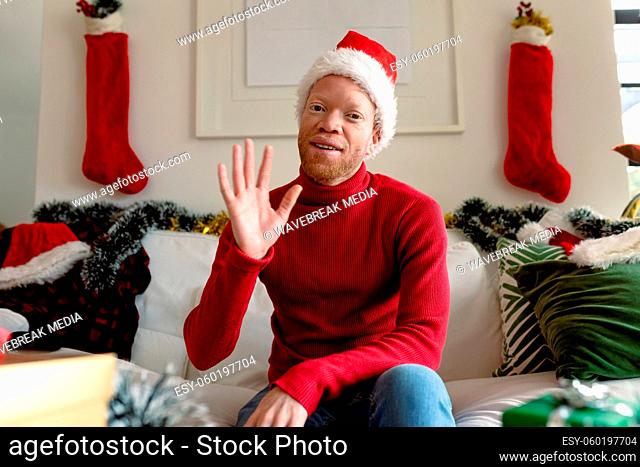 Albino african american man wearing santa hat making video call with christmas decorations