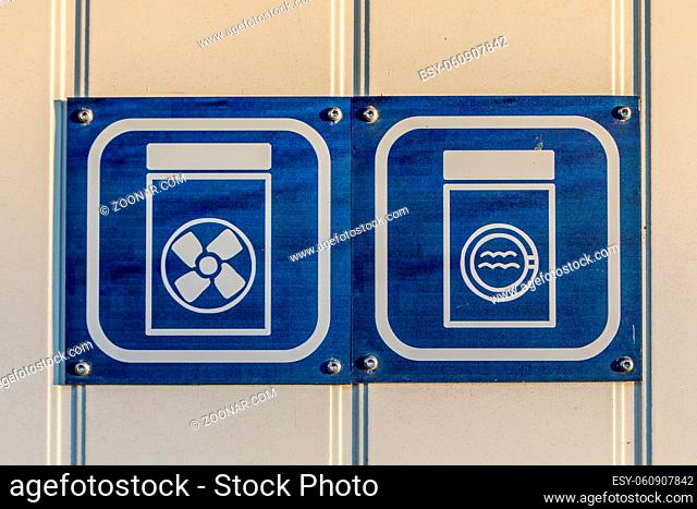 Signs showing illustration of washing machine and dryer, white and blue signs on white plank wall