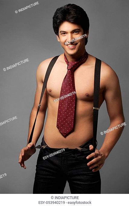 Portrait of shirtless man wearing suspenders and tie