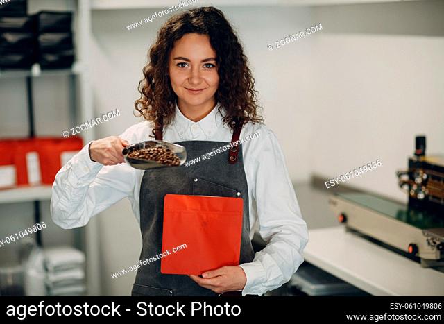 Fresh roasted coffee beans young worker woman packing machine in vacuum sealed bag