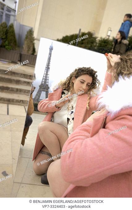 woman looking in mirror, outdoors in city, near tourist sight Eiffel Tower, at Espl. du Trocadéro, in Paris, France