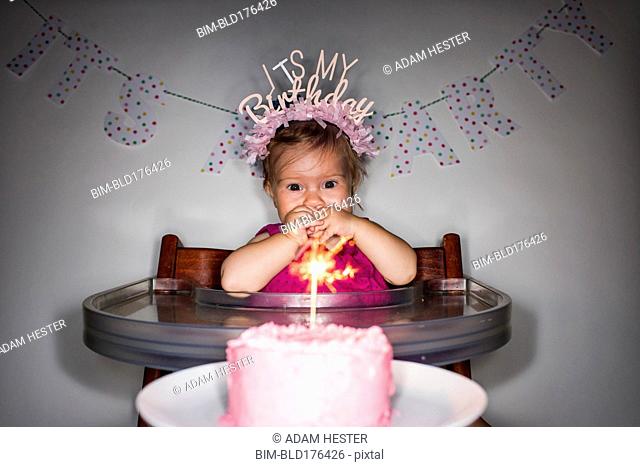 Caucasian baby girl admiring birthday cupcake