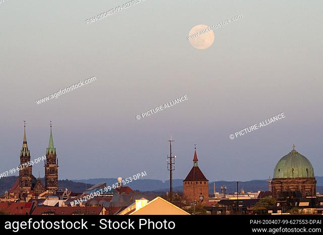 07 April 2020, Bavaria, Nuremberg: The moon rises as a so-called supermond, in the foreground you can see the towers of the church St
